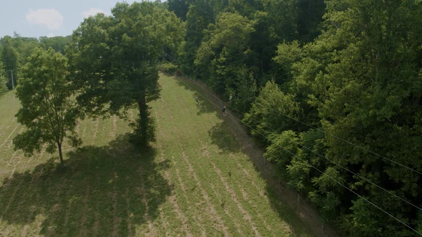 Three people zip line in rural area