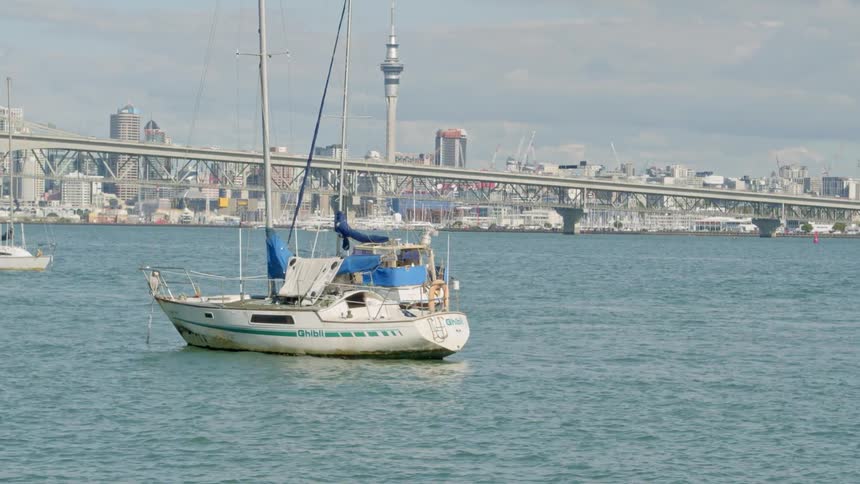 A sailboat is floating in the water next to a big city