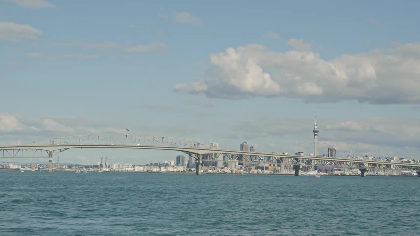 Boats travel in the water by a city bridge