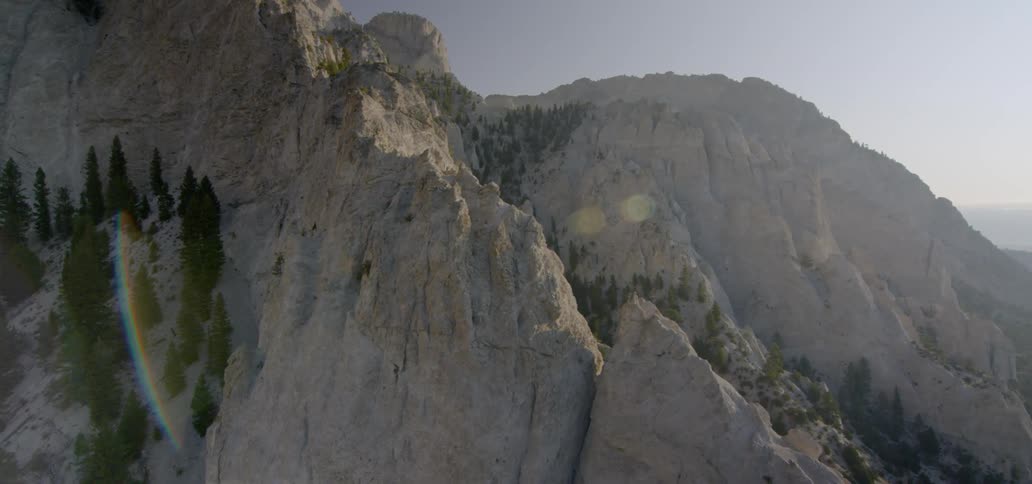 The mountain is tall with some trees on the side