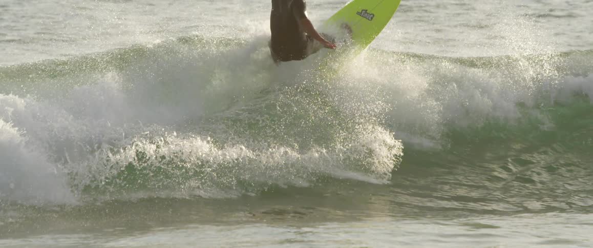 A man on a green surfboard is catching a wave
