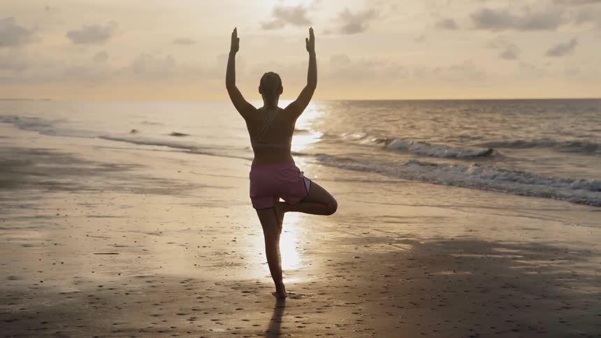 Woman practices yoga on a beach