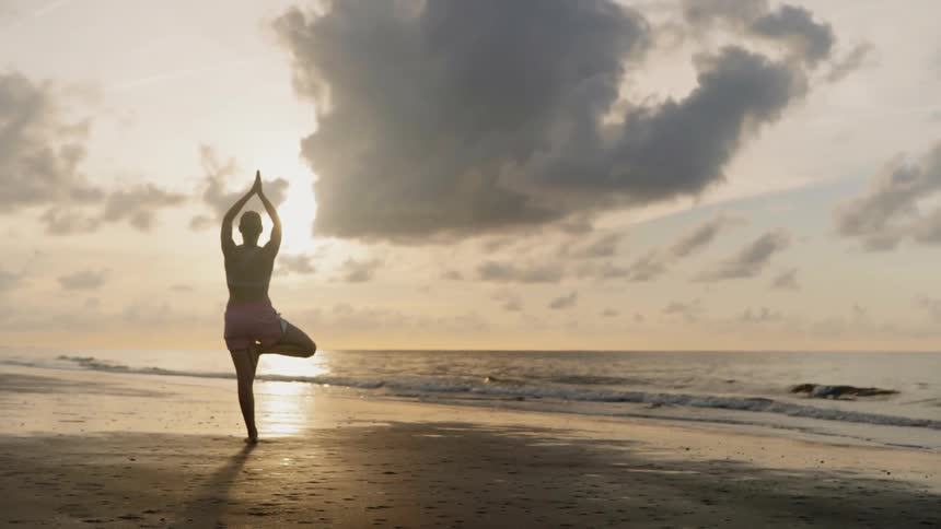 A woman is posing and doing yoga by the water