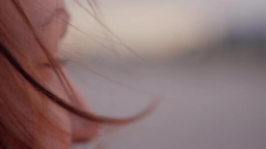 A red haired woman's hair blows in the breeze