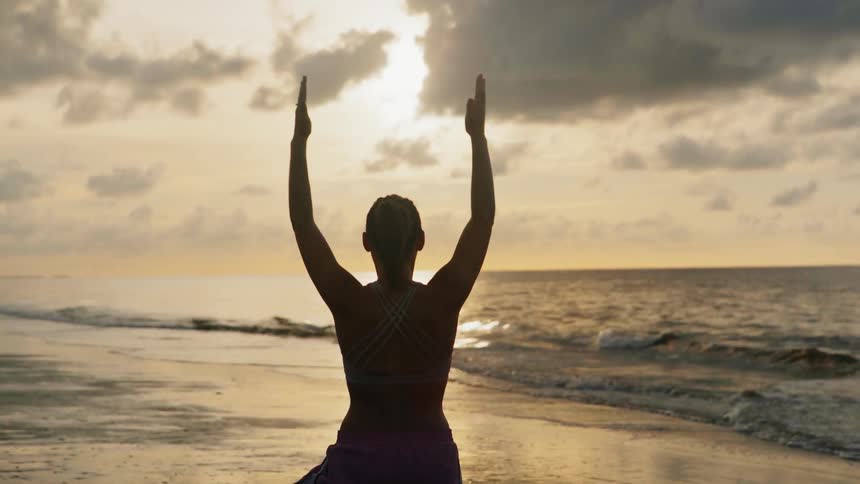 A woman does yoga on the beach