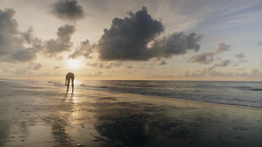 A woman does yoga on the beach