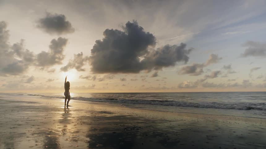 Person stands on the beach stretching arms