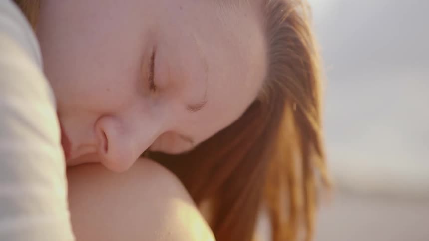 A woman sits on the beach as the wind blows