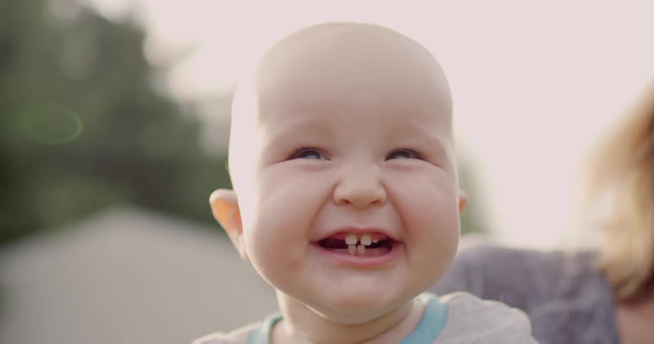 A woman and infant smile and laugh outside