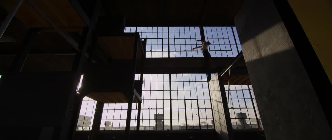 A man jumps from one surface to another inside a building