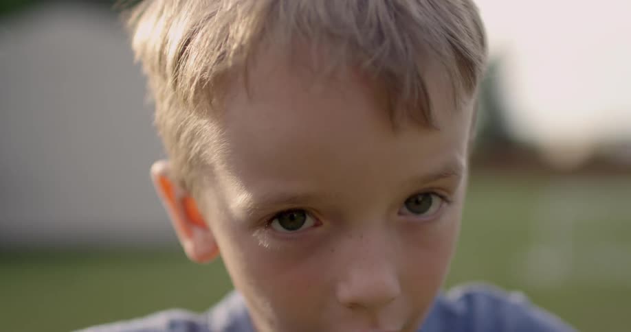 A young boy plays outside under the sun