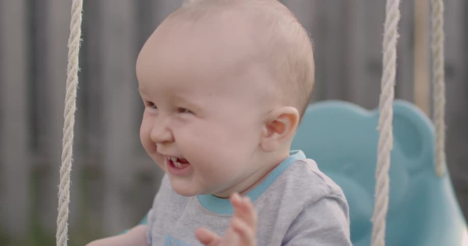 A baby is in a swing laughing