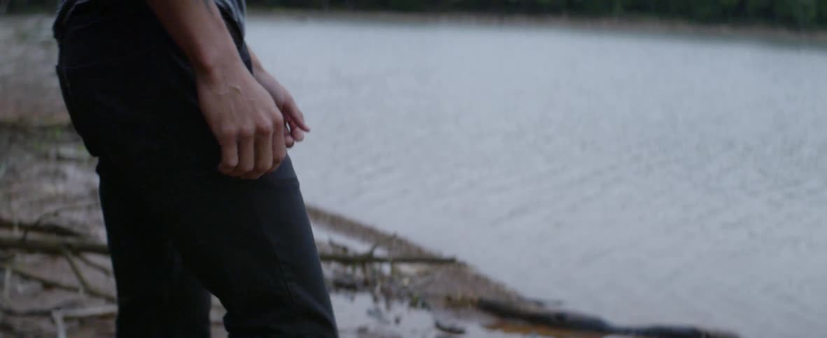 A man is walking to the edge of a river bank during the day