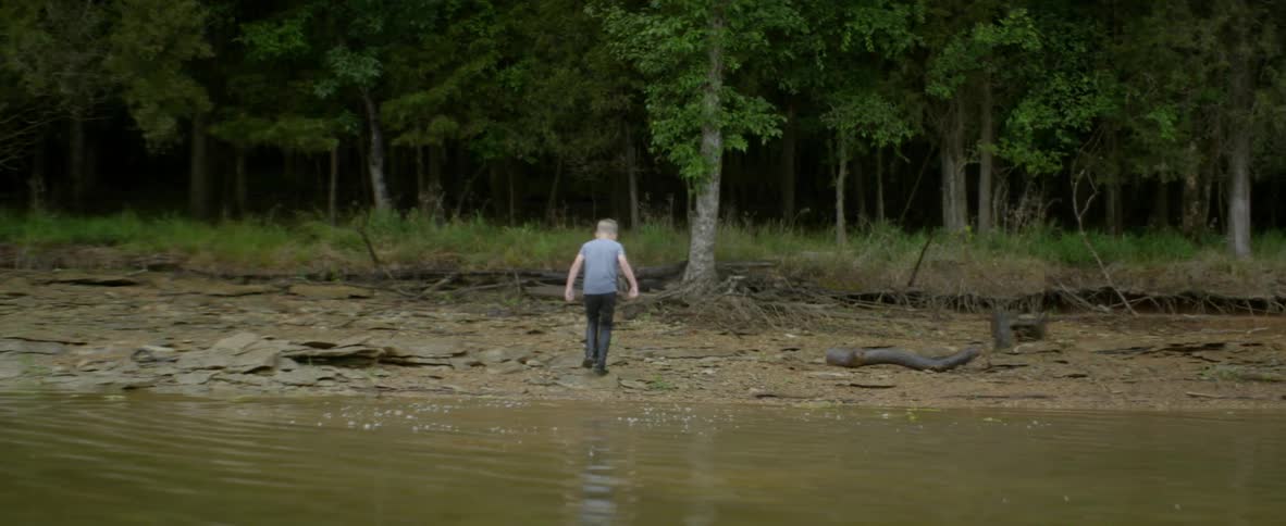 A young boy wades in a river