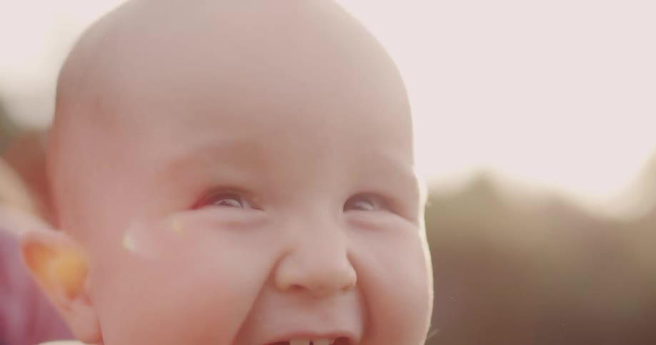 A baby laughs outside on a sunny day
