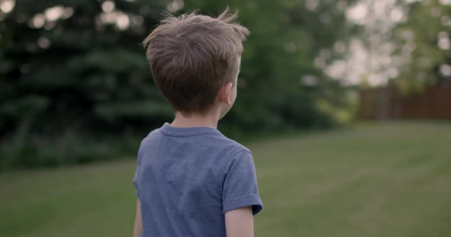 A young boy plays outside under the sun