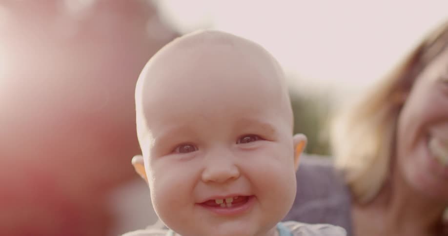 A woman and infant smile and laugh outside