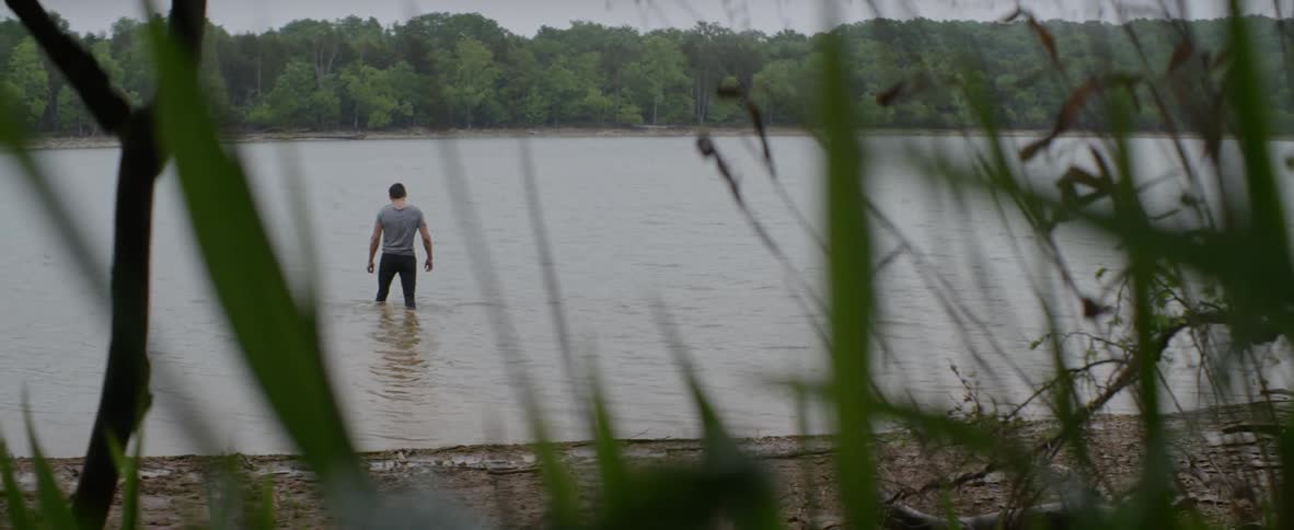 A man wades out into a lake