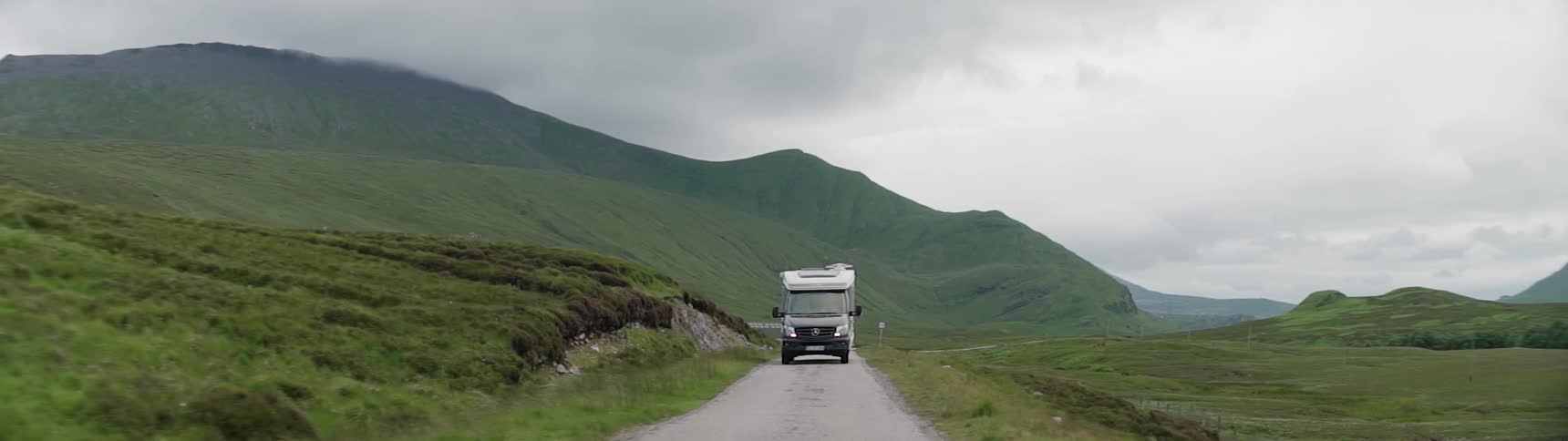The truck is moving along the road on a cloudy day