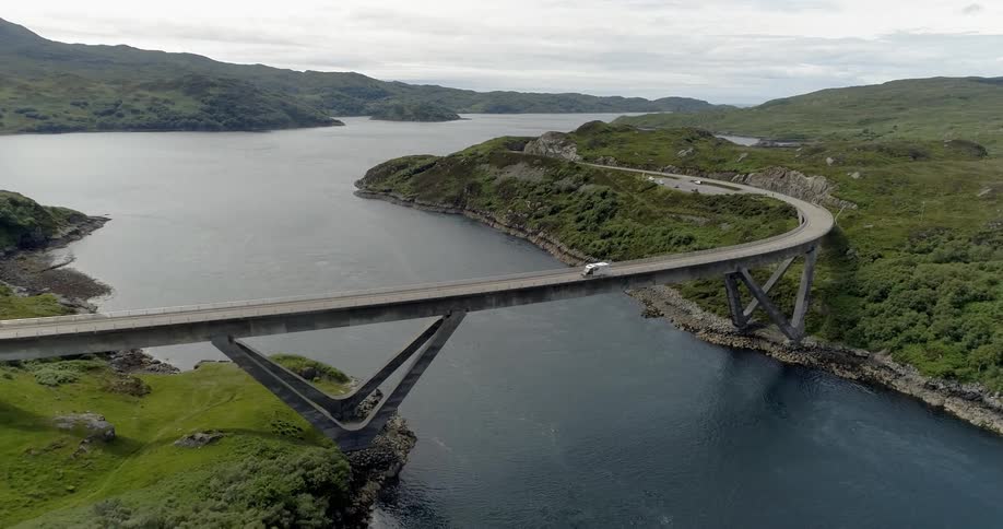 A car is driving across a bridge that is above a large lake