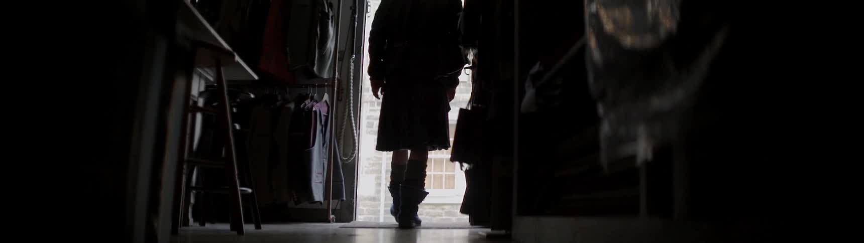 A man walks down the hall and peeks out the door