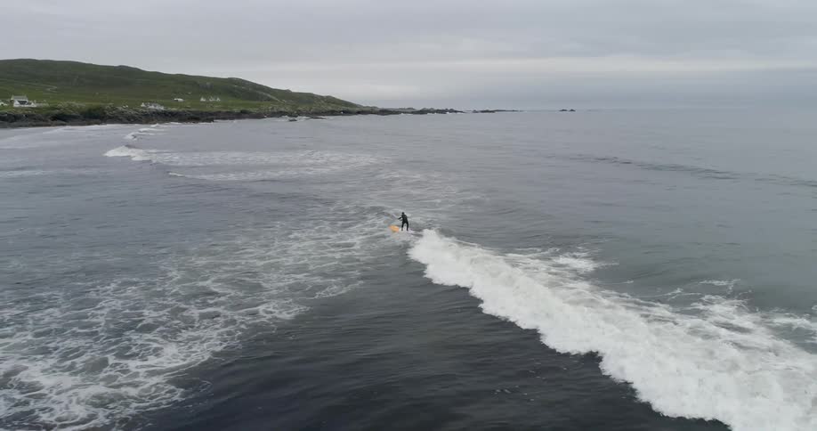 A surfer rides a wave towards the shore