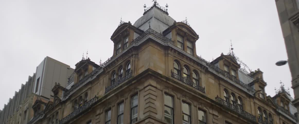 Bird flying near a building on a cloudy day