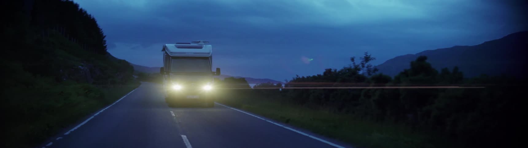 An rv is driven next to a lake at night