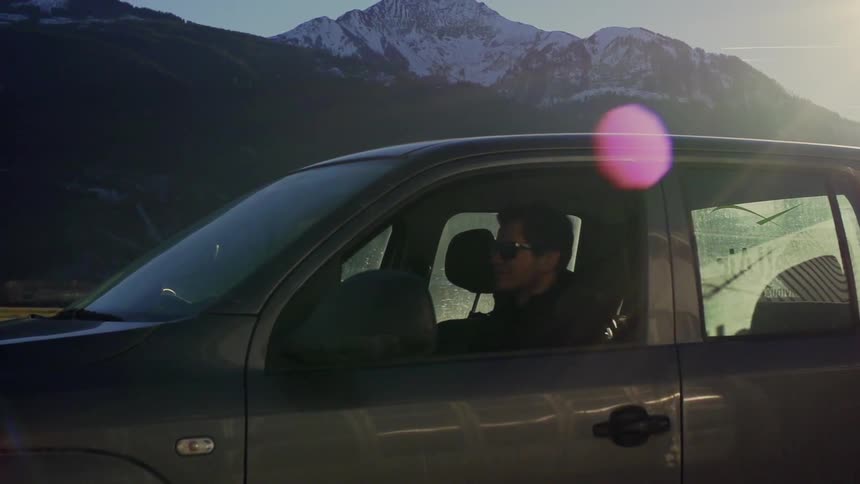 A man is sitting in his truck a mountain is in the background