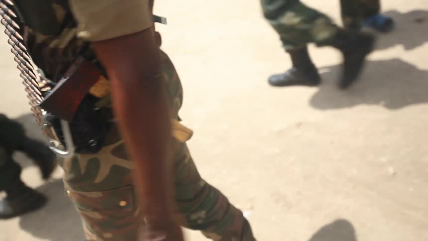 Black military soldiers walk along a dusty path