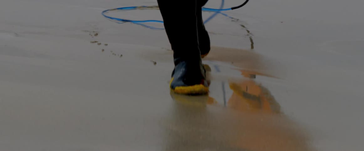 A man walks on the beach in wading boots
