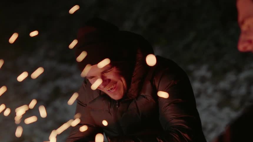 Man laughs outside by a fire at night