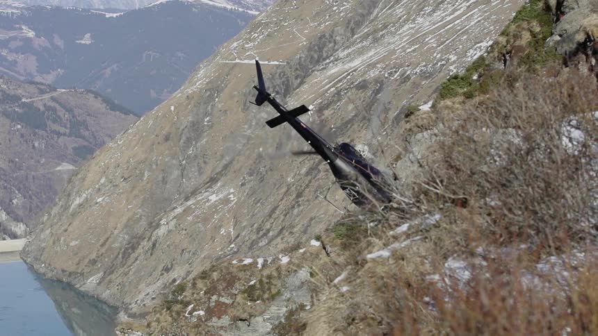 A black helicopter nosedives down towards the mountain