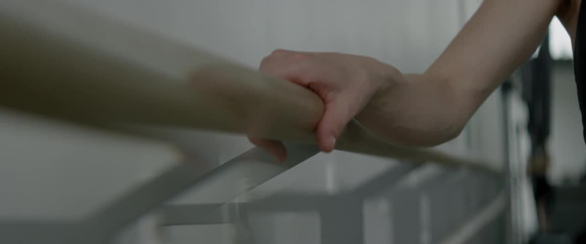 A dancer holds onto a ballet barre
