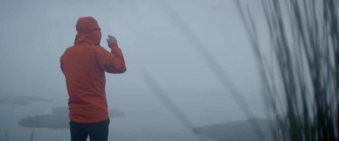 A man takes a photograph of a foggy lake