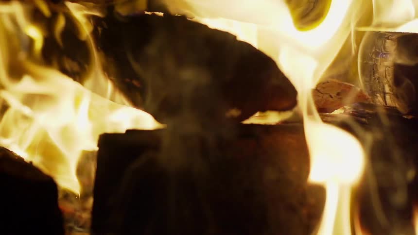 Smoke and flames rise from a wood log fire