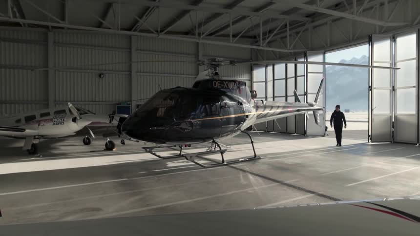 Man walks by helicopter and airplane parked in a garage