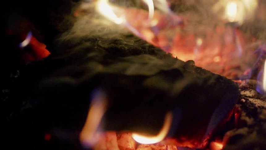 A close up of a fire and smoking pieces of wood