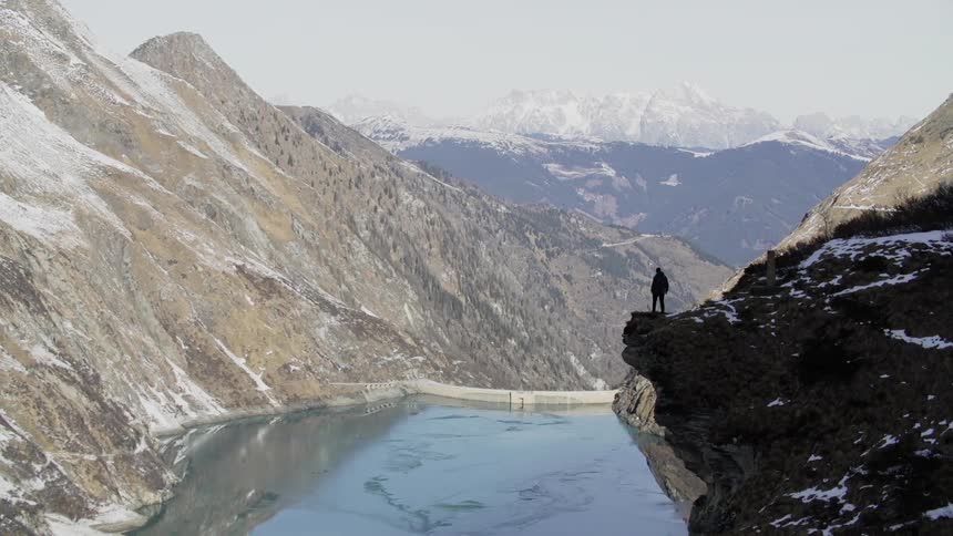 Person walks to the edge of a cliff overlooking a river