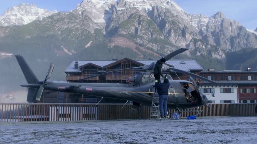 Two men inspect a helicopter parked in the snow