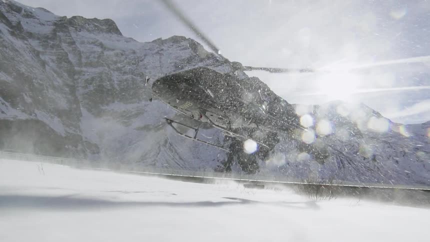 A helicopter hovers just above the snowy ground