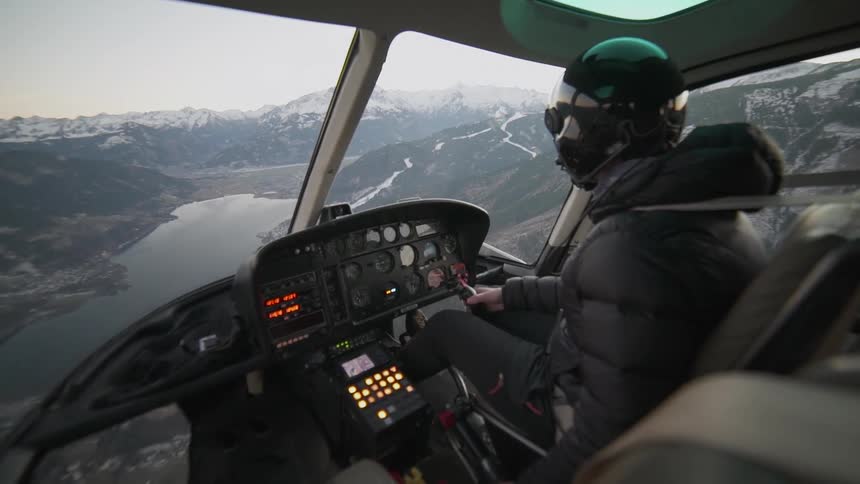 A helicopter is piloted between snowy mountains