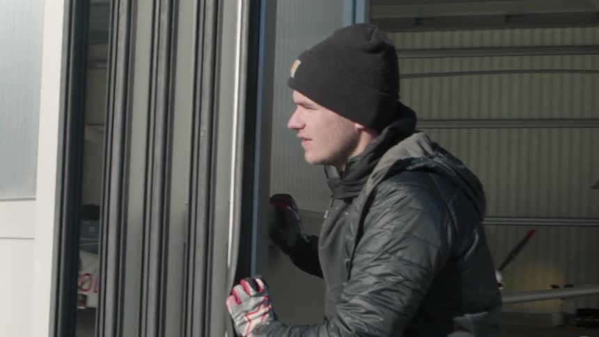 A man closes the door to an airplane hangar