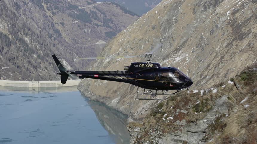 A helicopter hovers between mountains