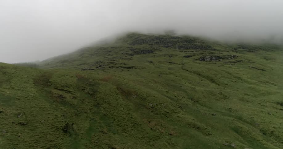 Clouds billow over grassy hills