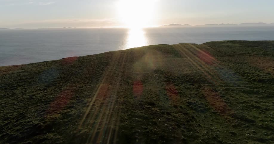 A green pasture leads to a cliff that overlooks the ocean