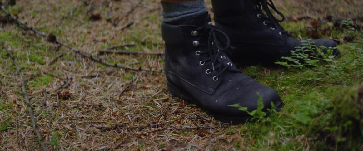 A person in boots stands on grassy ground