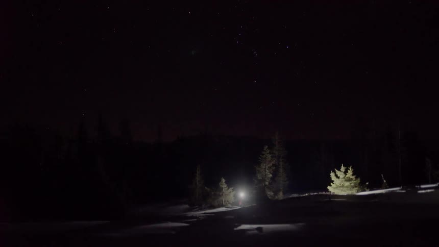 A man with a flashlight is walking up a dark hill