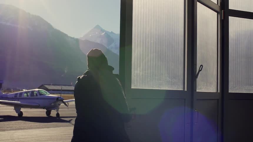 A man walks over to open the hangar door for the plane