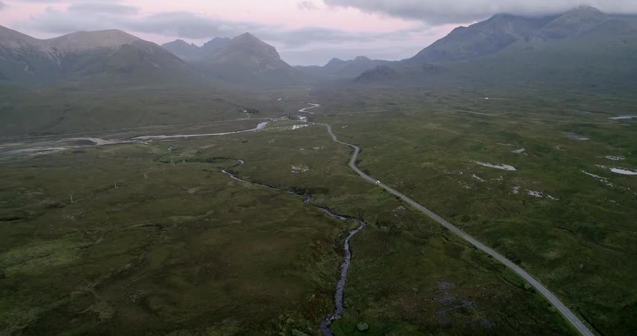 A green valley with many small streams running through it is viewed from above